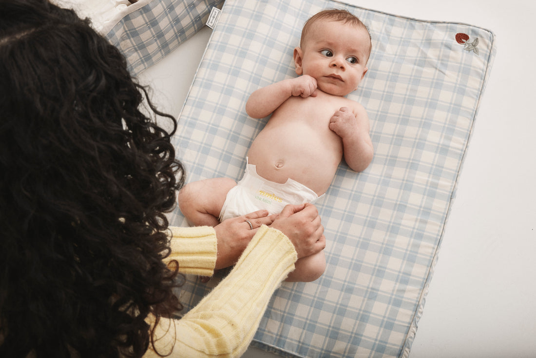 Bebis i Bammies bambublöja The Mini ligger på skötdyna medan förälder byter blöja