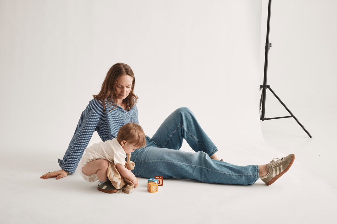 Förälder och barn leker på golvet med en blöja från Bammies under fotografering i studio