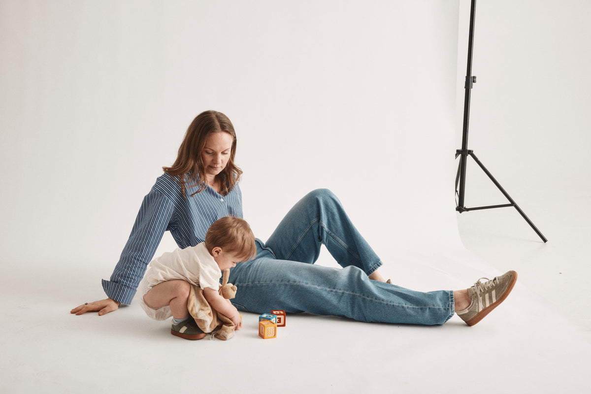 Förälder och barn leker på golvet med en blöja från Bammies under fotografering i studio