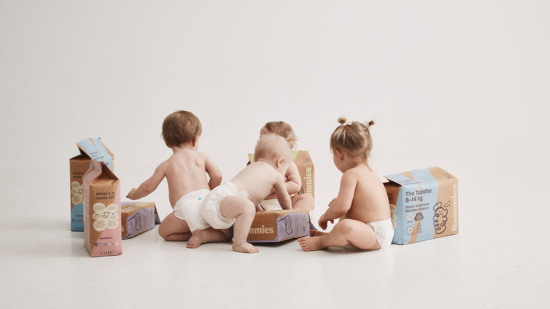 Fyra bebisar i Bammies bambublöjor sitter bland förpackningar med The Toddler 8–14 kg